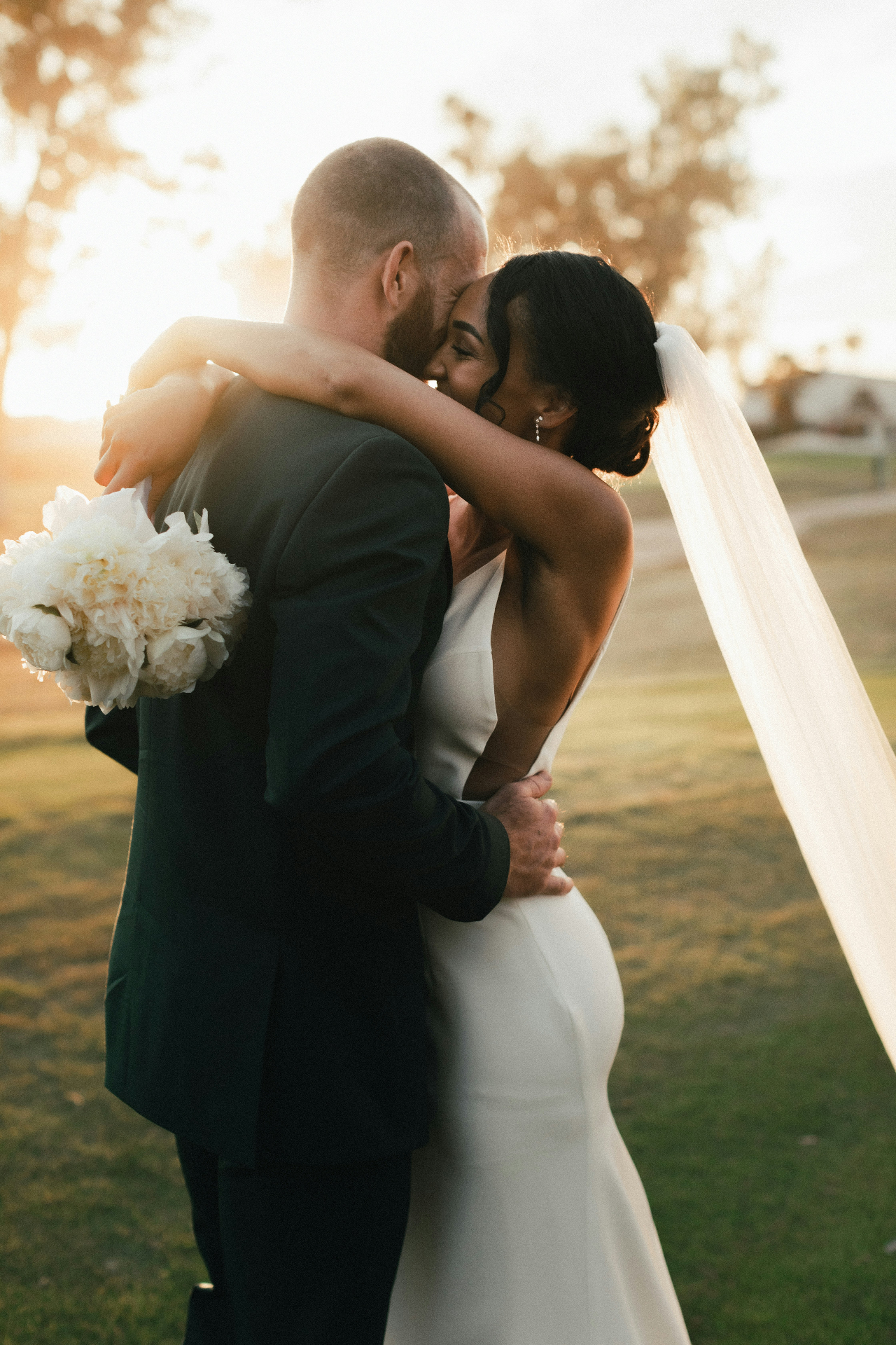 A couple in a sunlit garden, embodying a refined, elegant wedding day